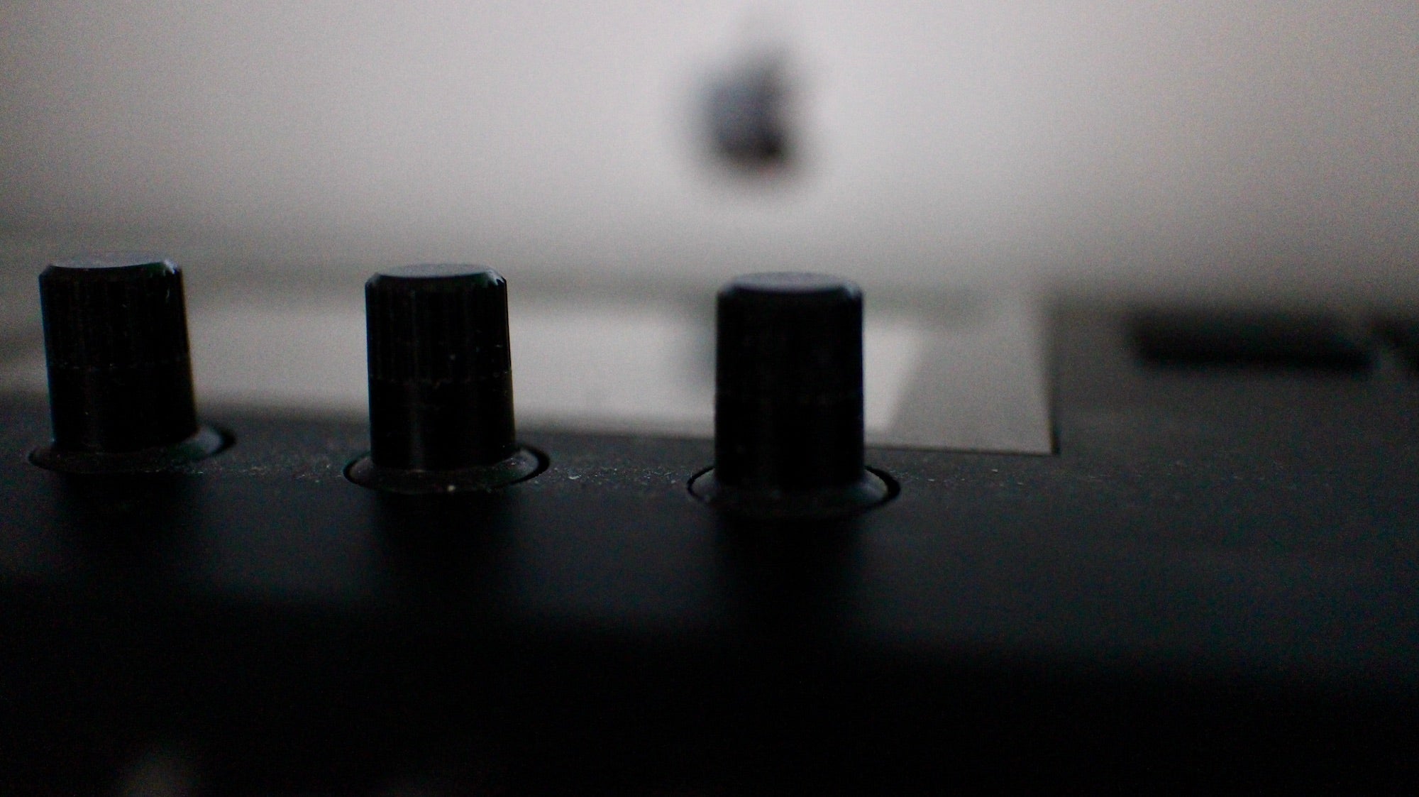 Close-up of black control knobs on a MIDI controller in a music studio, capturing a handmade and organic feel.